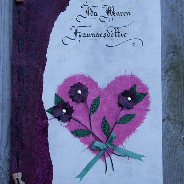 Myndanr. Z8 Forsðíðan skreytt með roði, pappírshjarta og roðblómum, fest saman með leðurreim og beintölum.  Marmarakarton 10 blöð með forsíðu, stærð A4.