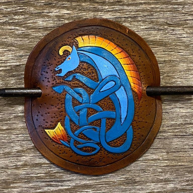 Sjalnæla eða hárnæla.  Handskorið í nautshúð og handlitað.  Keltneskt dýr.  Þvermál sa. 10 cm.
Verð.  7.500,- iskr.